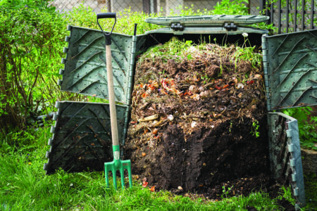 Layers of rotting compost in plastic composter bin in garden